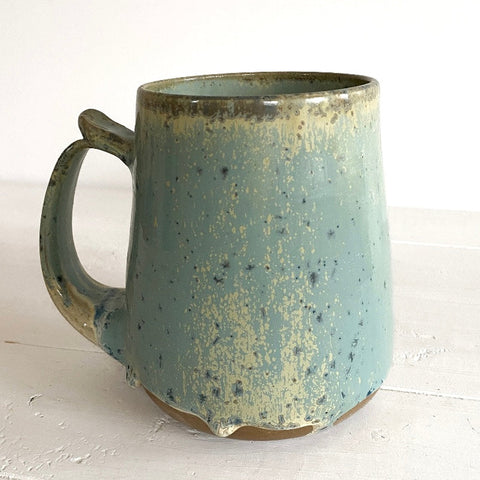 Speckled blue-green ceramic mug on a white surface
