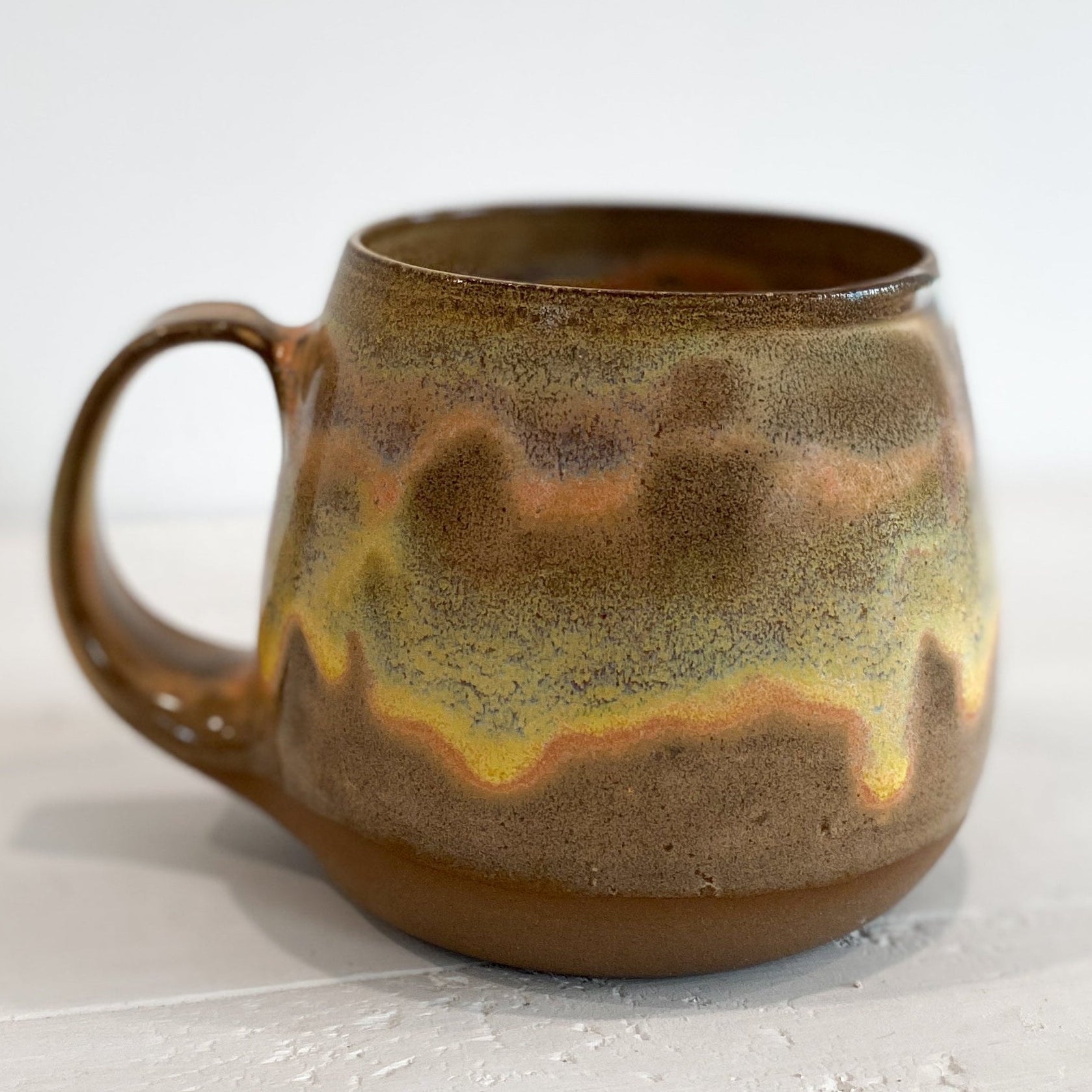 Stoneware mug with a unique glaze pattern on a white background