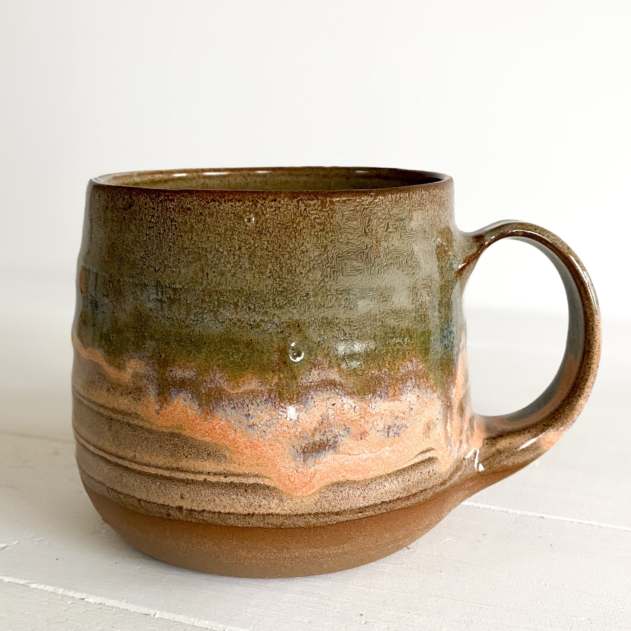 Ceramic mug with a brown and green glaze on a white surface
