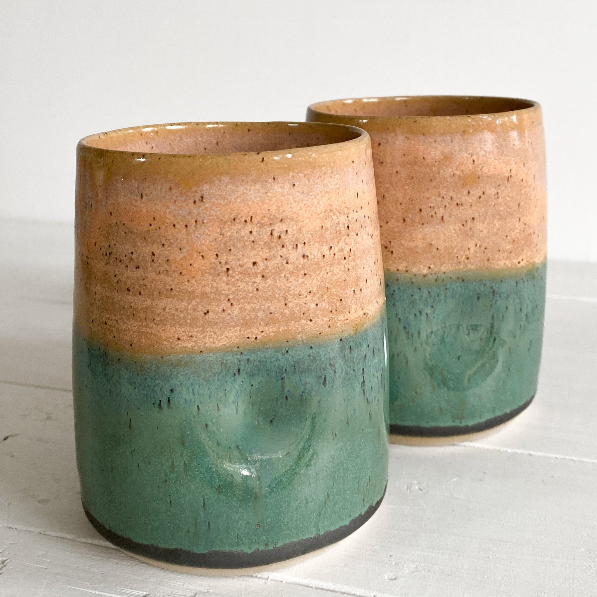 Two ceramic cups with a two-tone design on a white surface