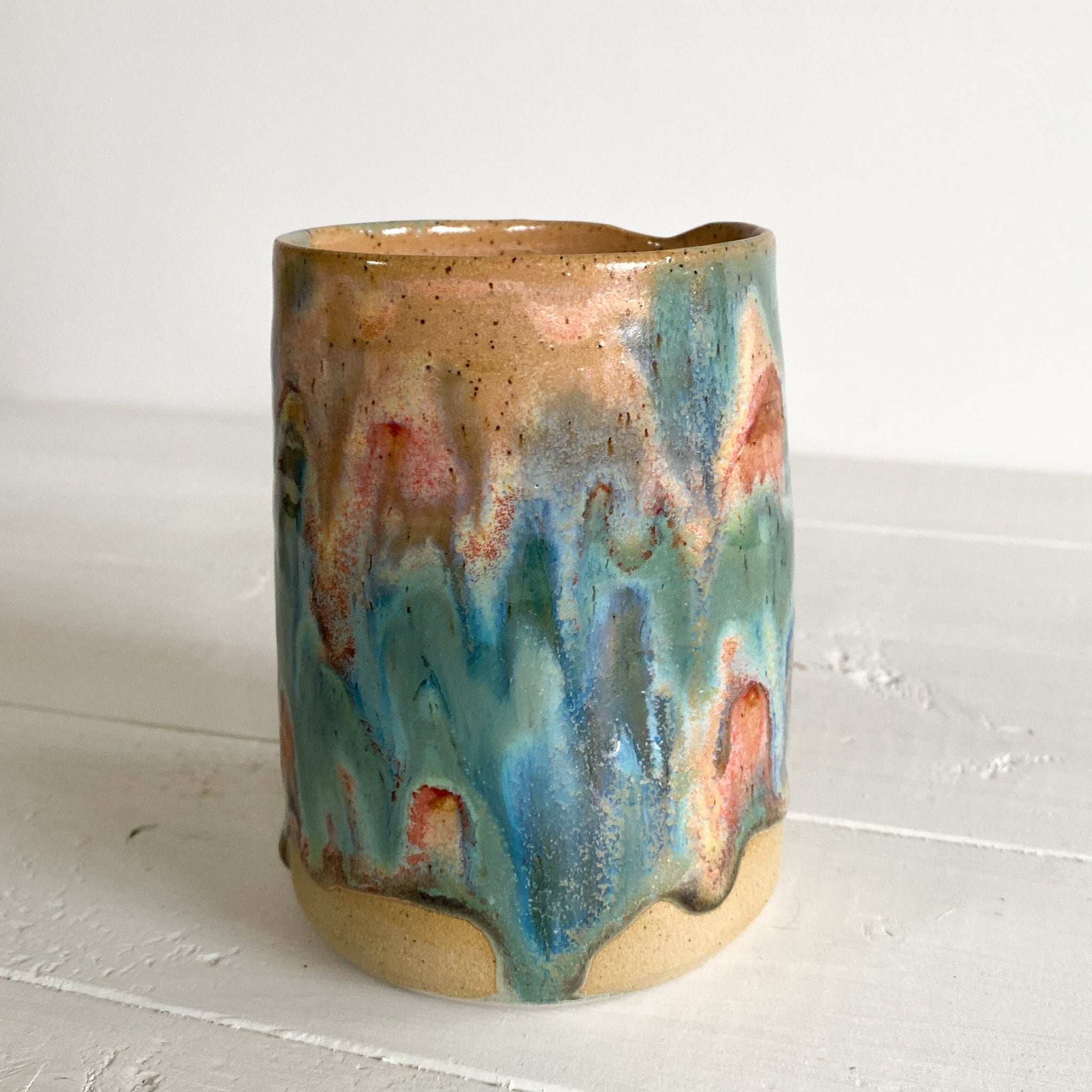 Ceramic mug with multicolored glaze on a white surface