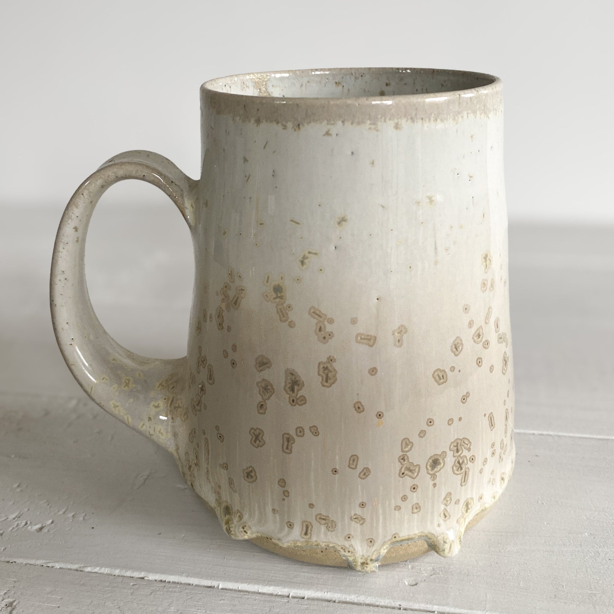 Speckled ceramic mug on a light wooden surface with a white background