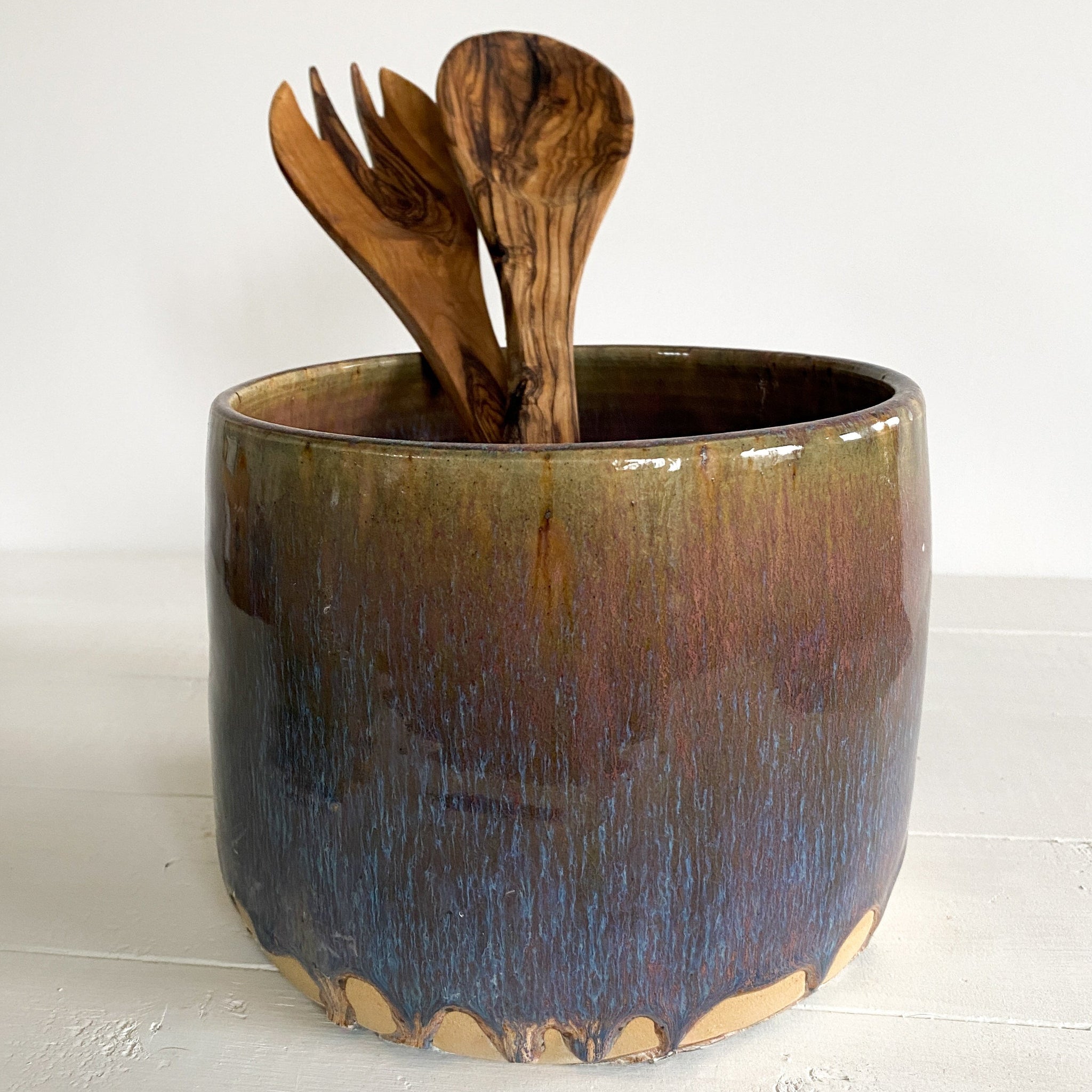 Ceramic container with wooden utensils on a white surface
