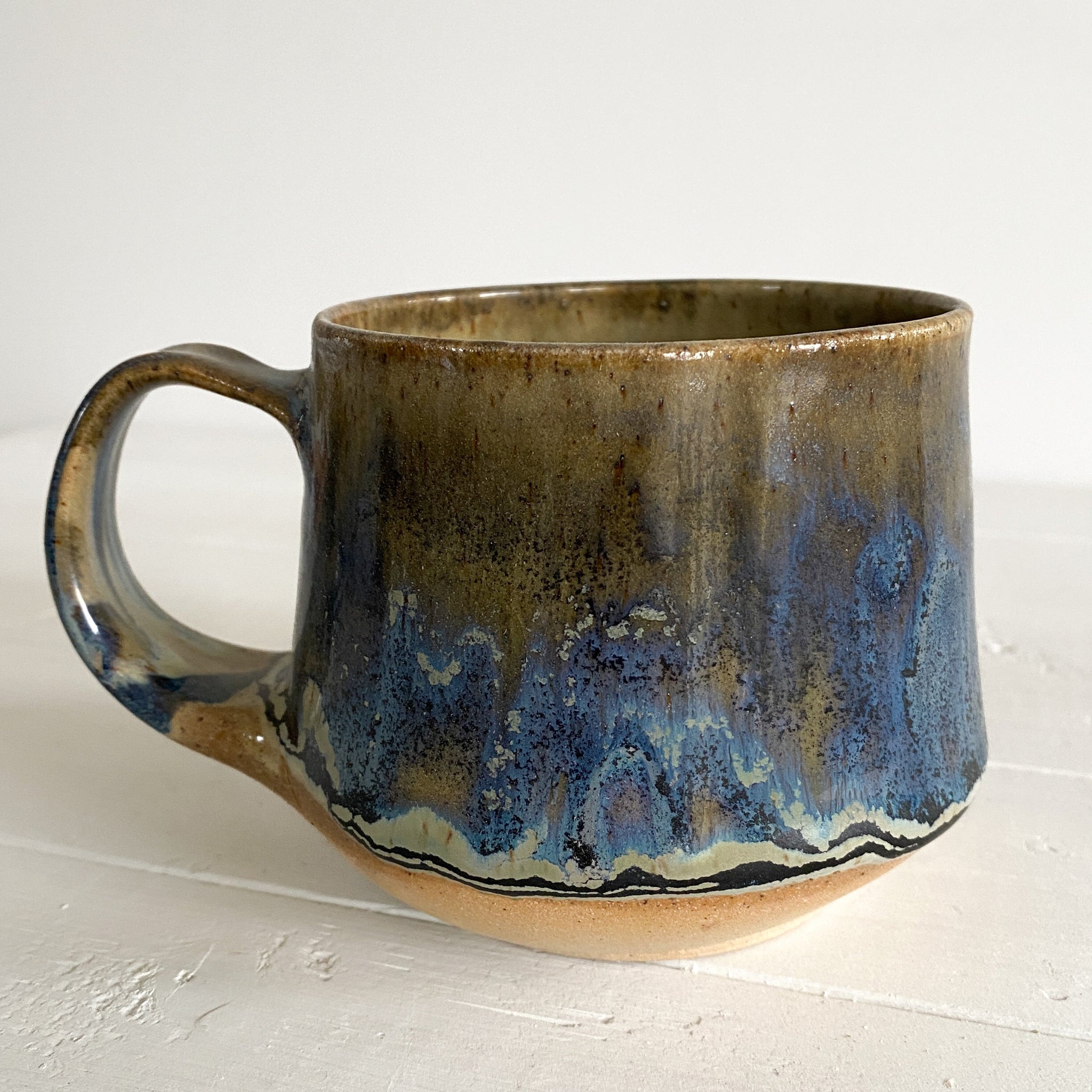 Ceramic mug with blue and brown glaze on a white surface