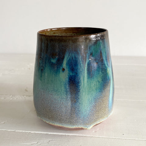Ceramic cup with blue and green glaze on a white surface