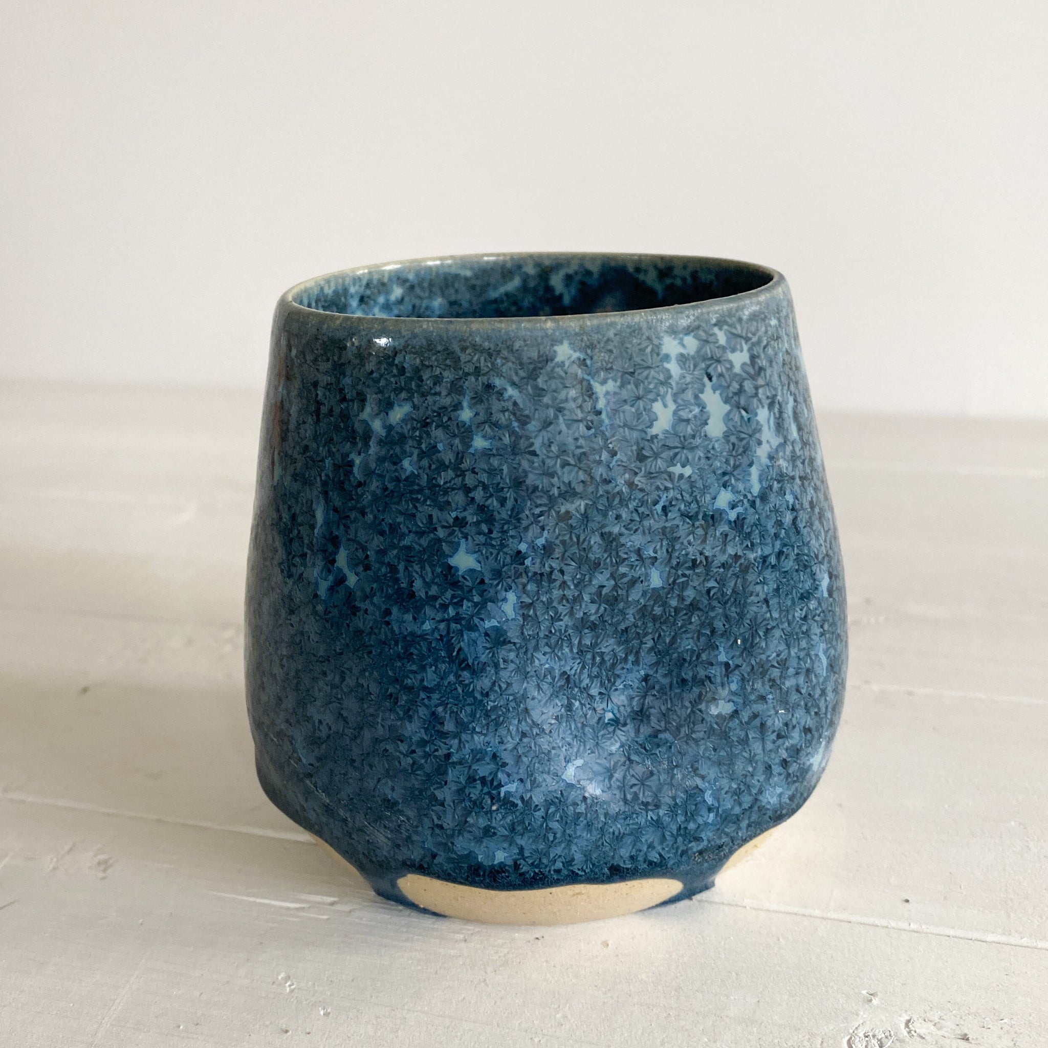 Blue ceramic cup on a white surface with a white background