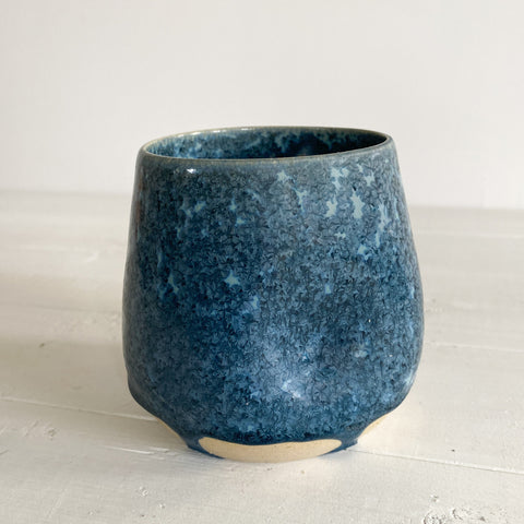 Blue ceramic cup on a white surface with a white background