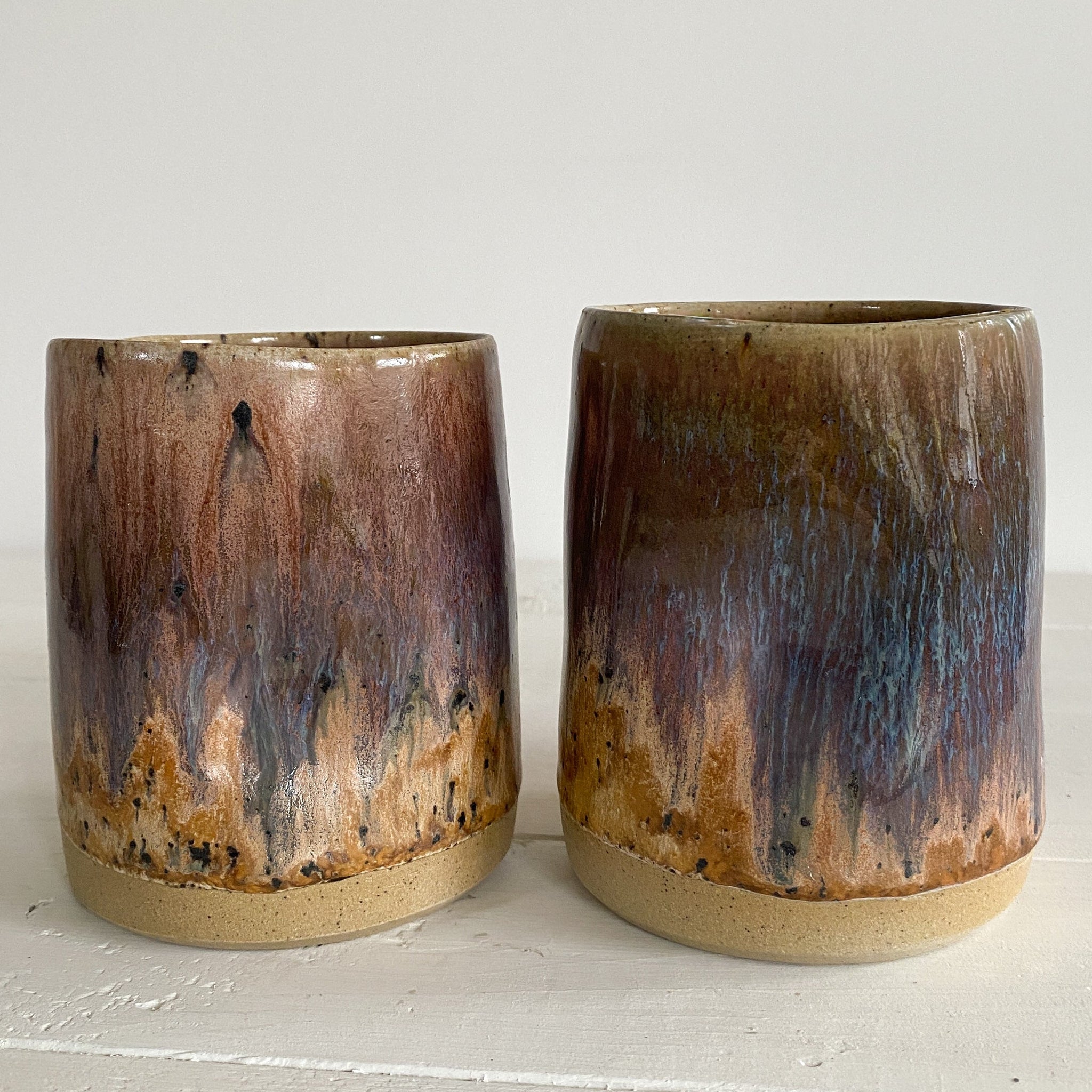 Two ceramic cups with a gradient finish on a light surface.