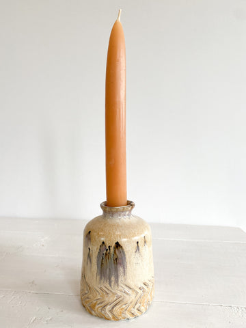 Ceramic candle holder with a tall candle on a white surface