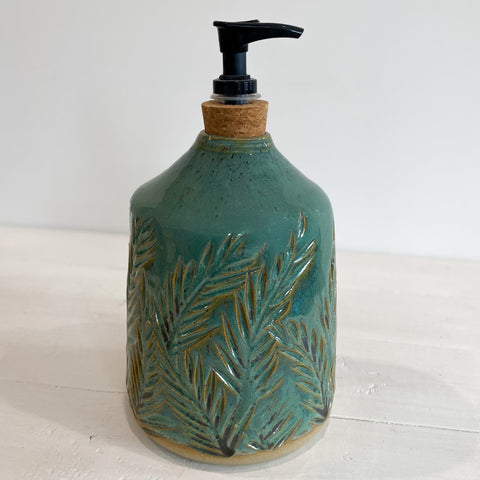 Ceramic soap dispenser with leaf pattern on a white surface