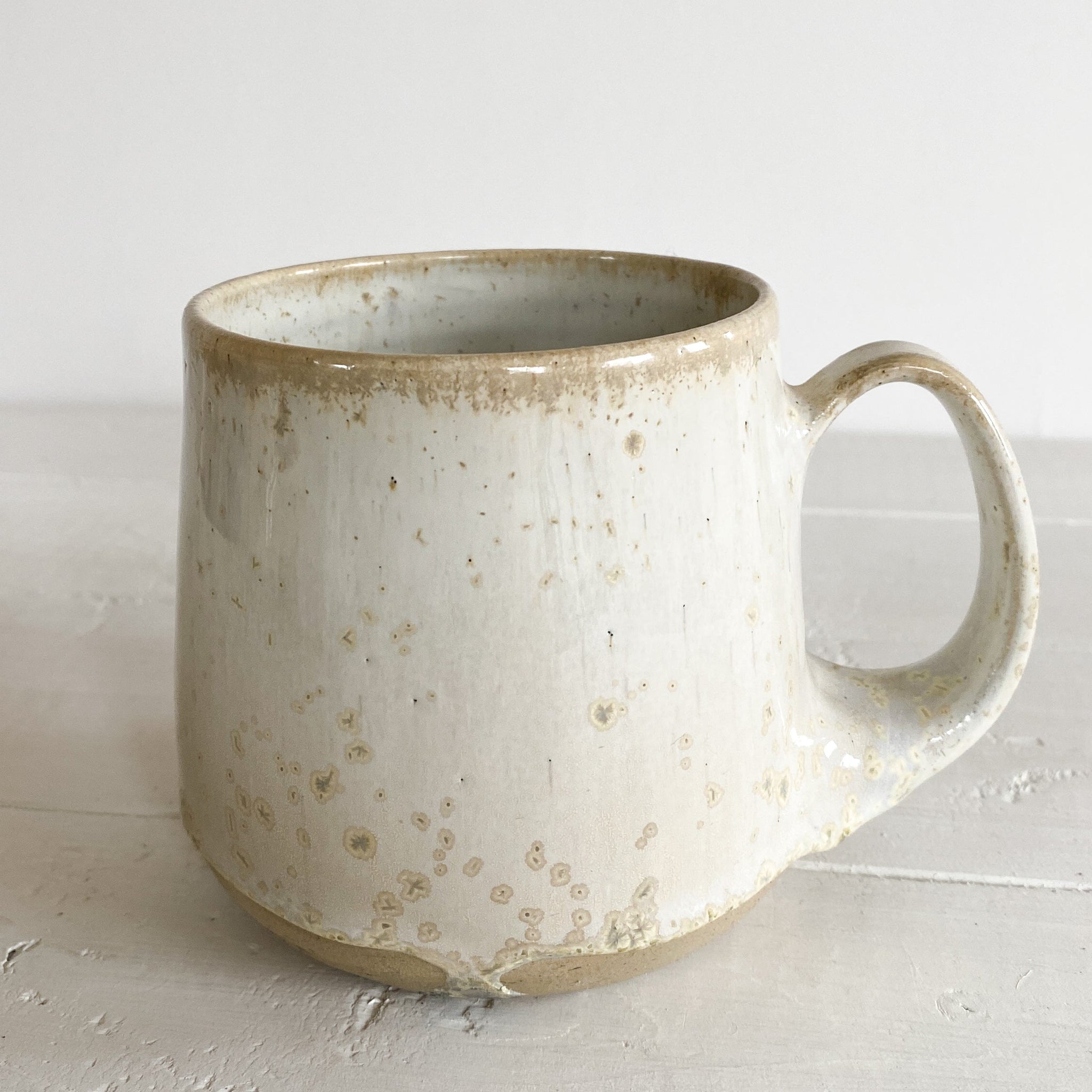 Speckled ceramic mug on a white wooden surface