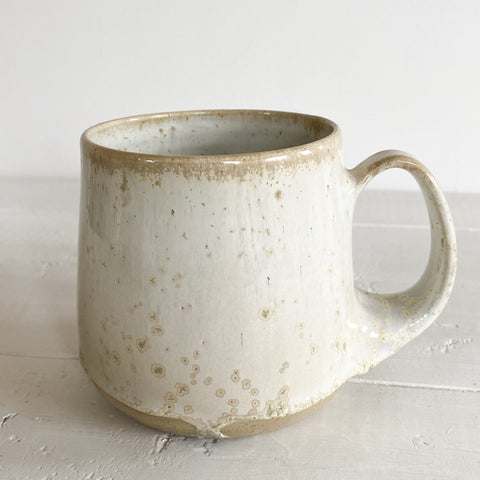 Speckled ceramic mug on a white wooden surface
