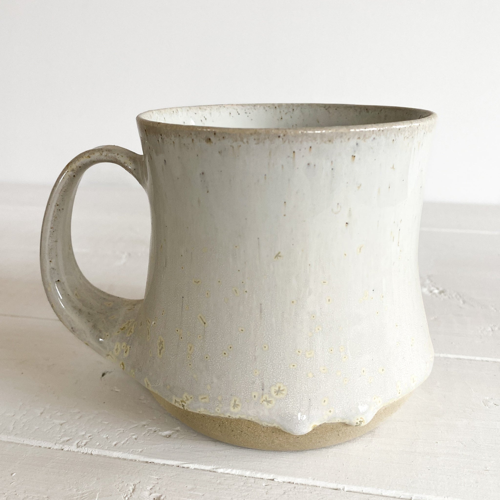 White ceramic mug with speckled texture on a white surface