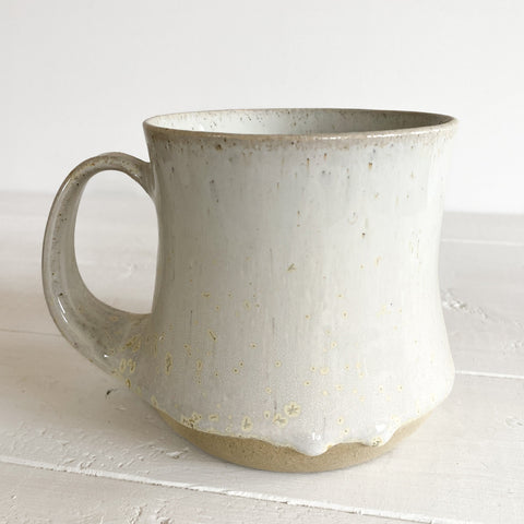White ceramic mug with speckled texture on a white surface