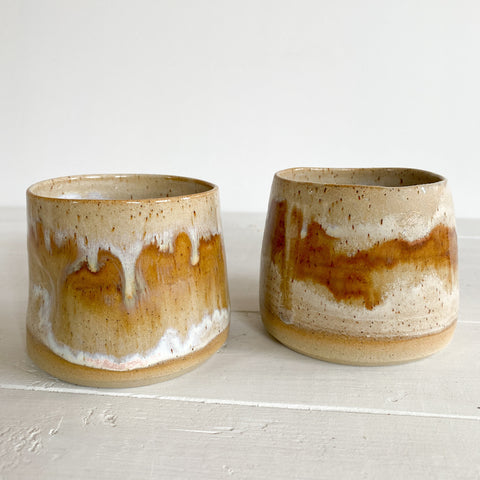Two ceramic pots with brown and white glaze on a light gray background