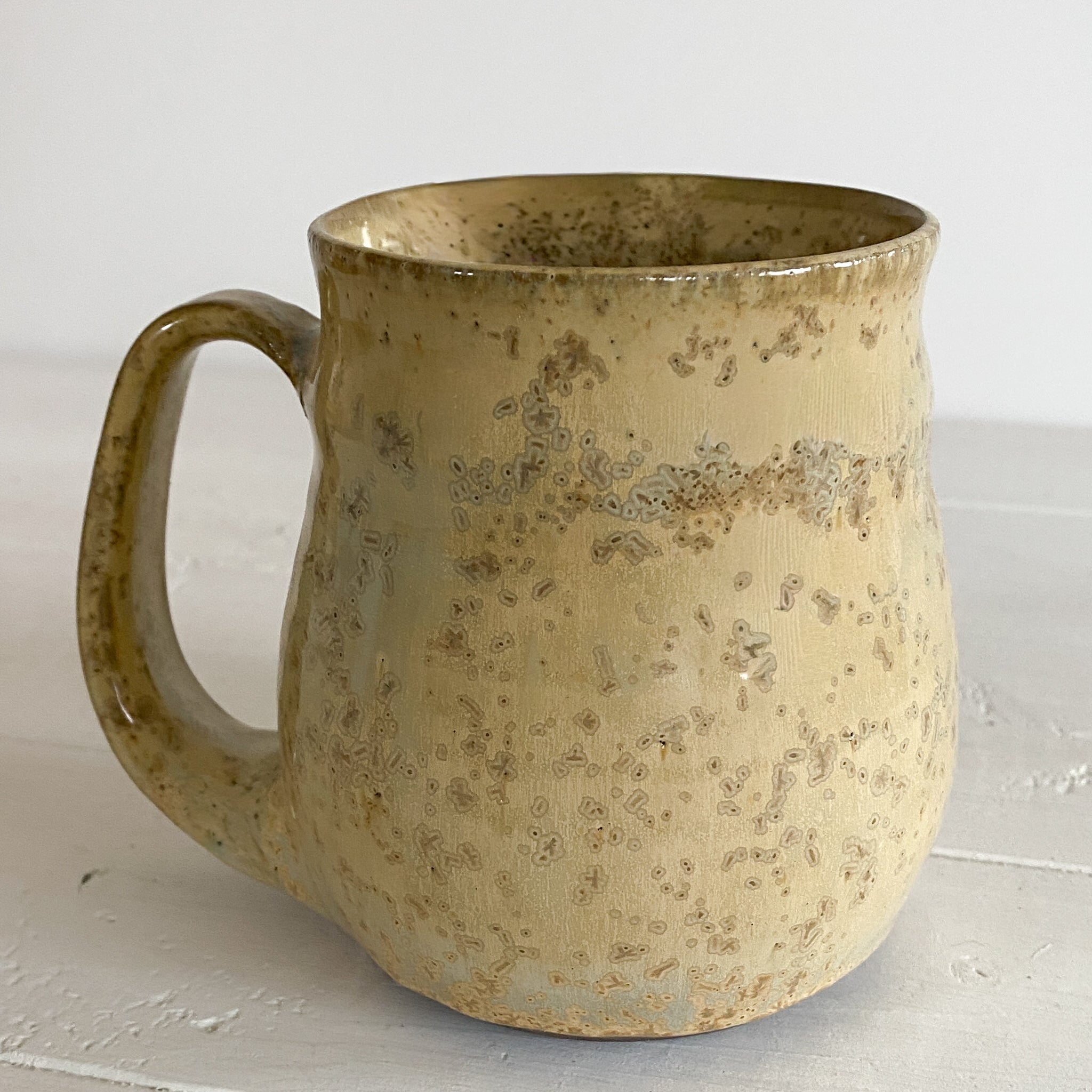 Speckled brown ceramic mug on a light wooden surface
