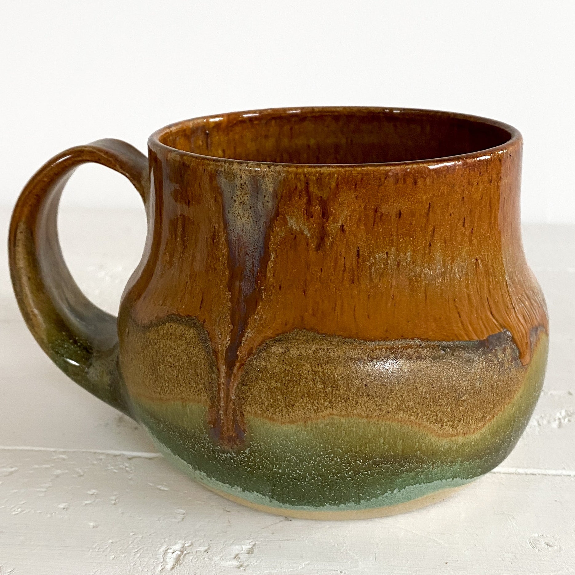 Brown and green ceramic mug on a white surface
