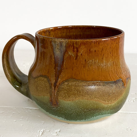 Brown and green ceramic mug on a white surface