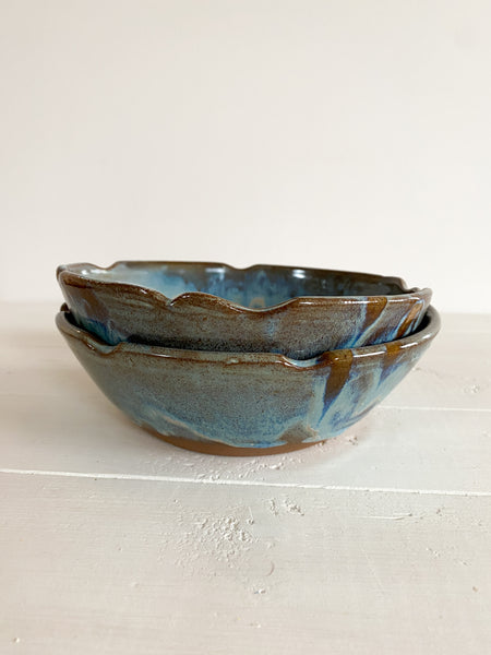 Stack of ceramic bowls with blue and brown glaze on a light background