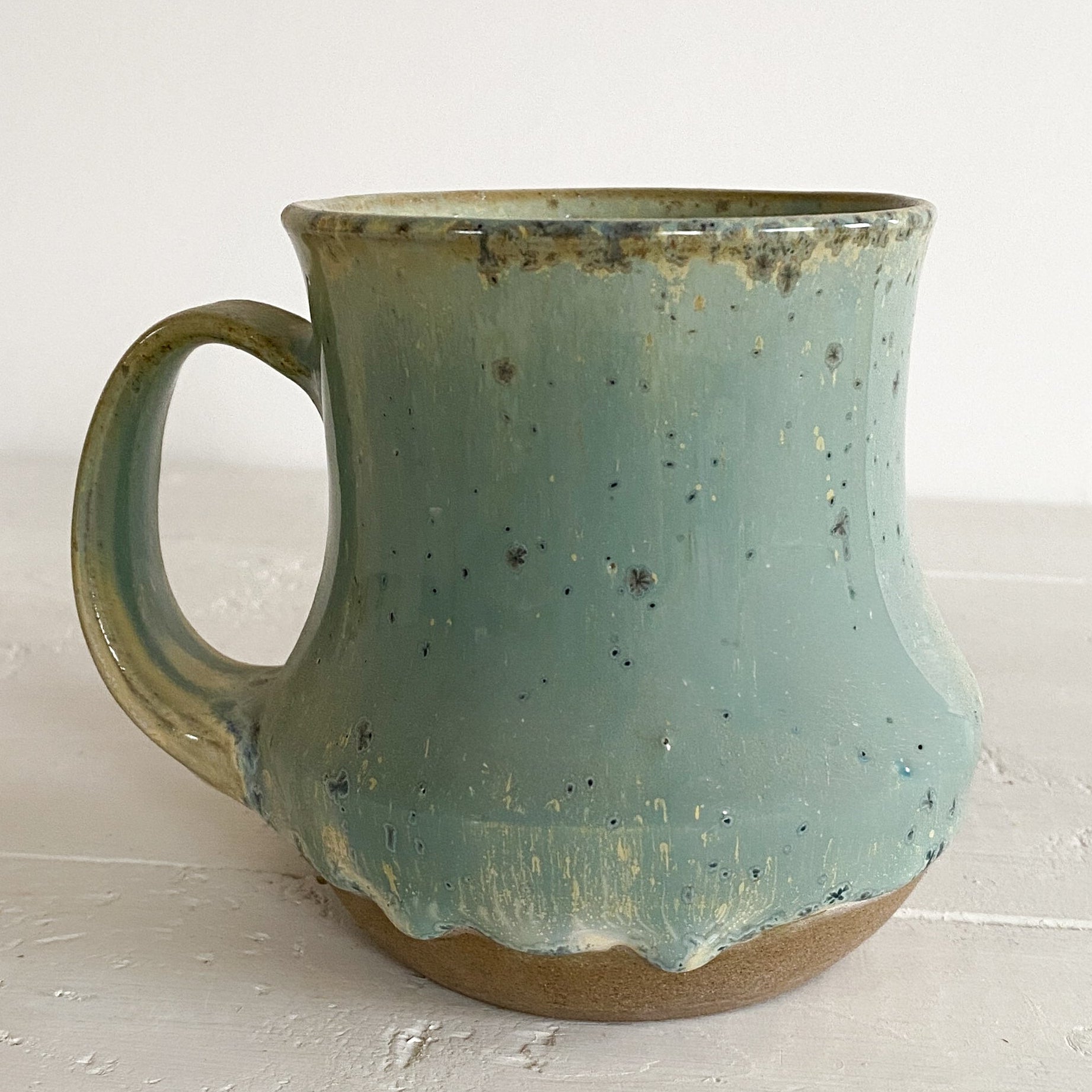 Blue ceramic mug on a white surface with a white background