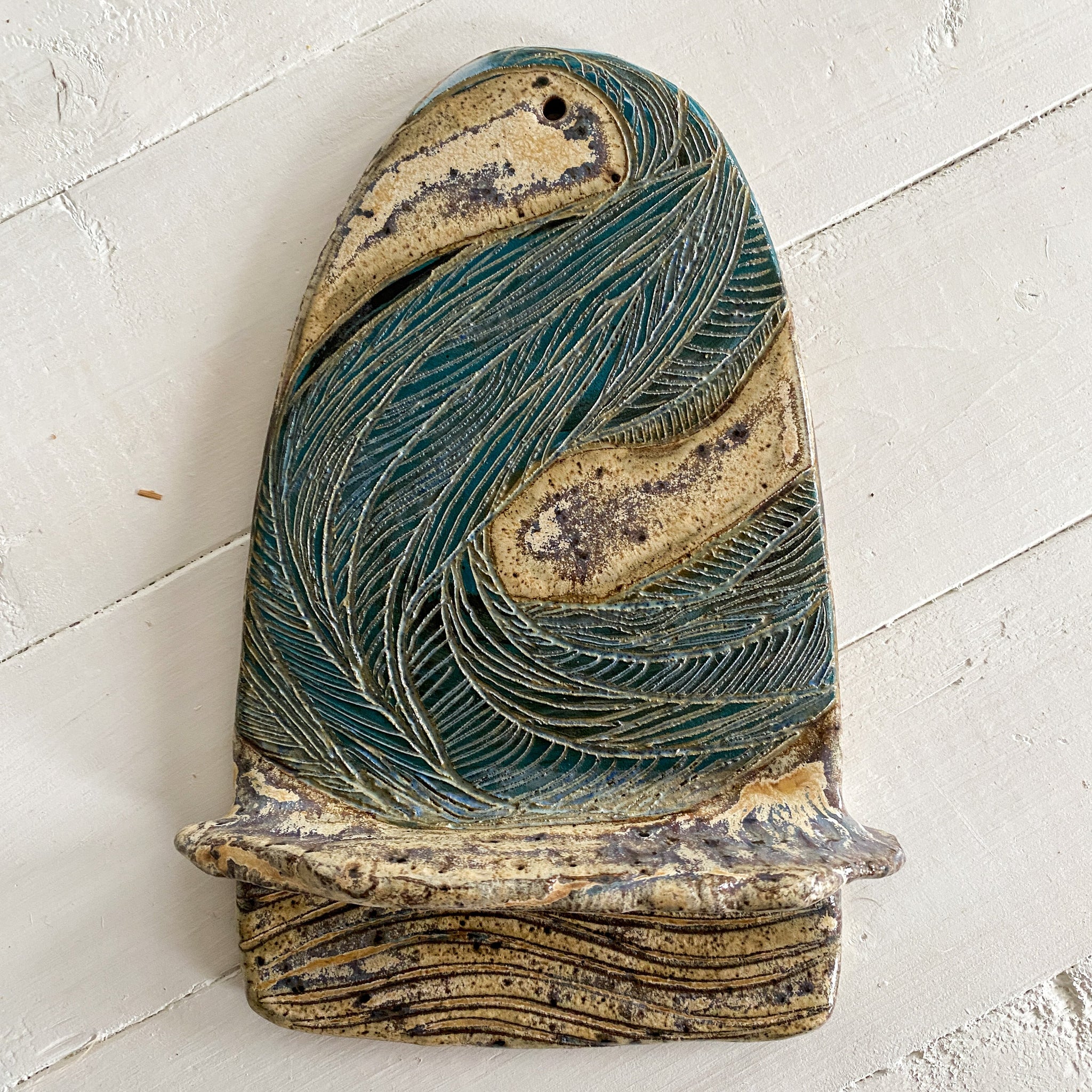 Ceramic wall sculpture of waves on a textured white surface