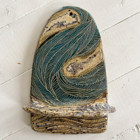 Ceramic wall sculpture of waves on a textured white surface