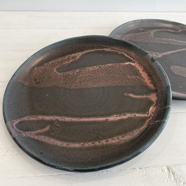 Two ceramic plates with brown glaze on a white surface
