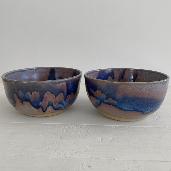 Two ceramic bowls with blue and brown glaze on a light gray surface.