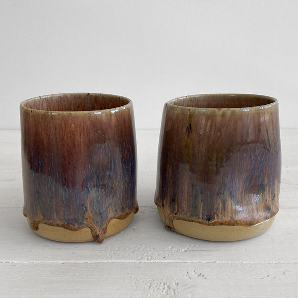 Two brown ceramic tumblers on a white surface with a white background