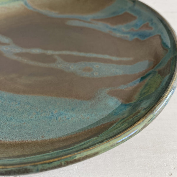 Ceramic plate with green and brown glaze on a white background
