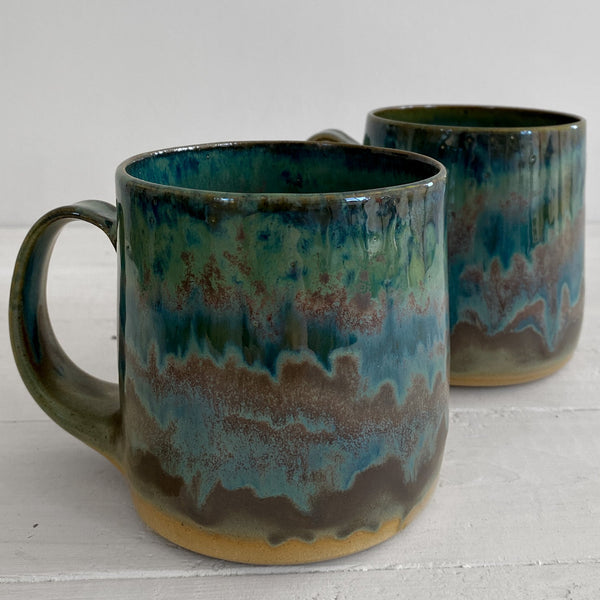 Two ceramic mugs with a multicolored glaze on a white surface