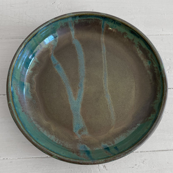 Ceramic bowl with blue and brown glaze on a white wooden surface