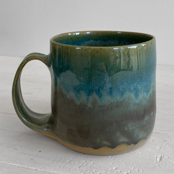 Green ceramic mug on a light gray surface with a white background