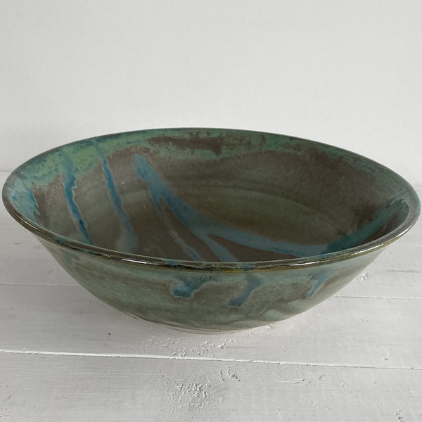 Green ceramic bowl with blue accents on a white wooden surface