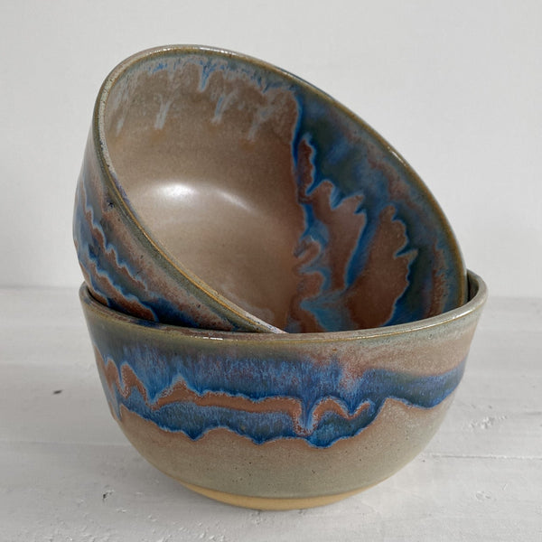 Two ceramic bowls with blue and brown glaze on a white surface