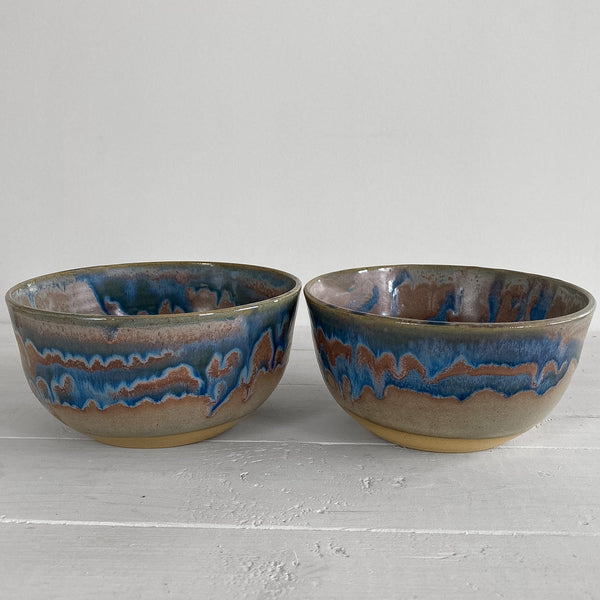 Two ceramic bowls with blue and brown glaze on a light gray surface