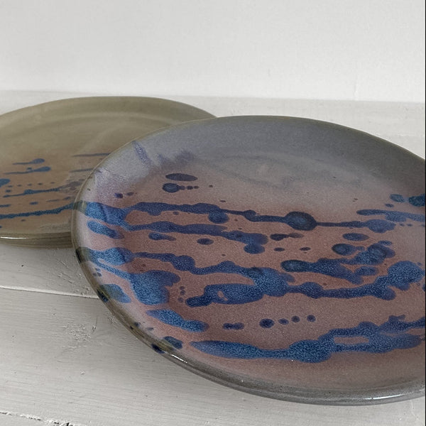 Two ceramic plates with blue abstract patterns on a white surface