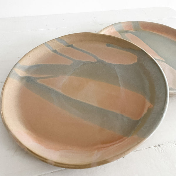 Two ceramic plates with abstract brown and pink design on a white surface